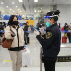 Un trabajador del aeropuerto de Pekín revisa la documentación de una viajera el pasado domingo. 