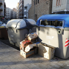 Cajas al lado de un contenedor de papel y cartón en la plaza Santa Maria Magdalena (Clot).