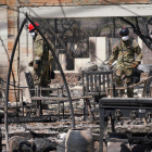 Dos soldats inspeccionen les restes d’un habitatge arrasat pel foc.