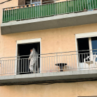 Un agent de la policia científica surt del balcó del pis incendiat a Figueres en la investigació de les causes del foc.