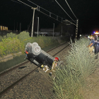 El cotxe bolcat sobre la via del tren i els serveis d’emergències que es van desplaçar fins al lloc.