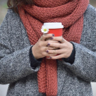 Una chica abrigada sujetando un café, en una imagen de archivo.