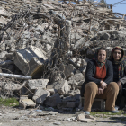 Dos mujeres sentadas frente a los escombros de una casa en el centro de la aldea turca de Ordekdede.