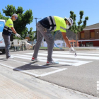 Operaris pintant un dels passos zebra de Mequinensa.