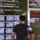 Un hombre mira los anuncios con ofertas de viviendas disponibles en una inmobiliaria. 