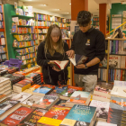 Dos jóvenes, esta semana en la librería Caselles de Lleida ante un expositor de novedades literarias.
