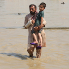 Un hombre sostiene a un niño en una zona inundada.