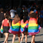 Cuatro chicas de espaldas con la bandera LGTBI durante el desfile del Pride de Barcelona