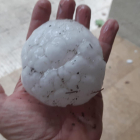 Una persona aguanta una piedra que ha caído este martes por la tarde en Corçà.