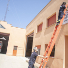 Dos bomberos voluntarios colgando ayer la pancarta en el parque de Agramunt. 