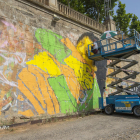 L’artista Llukutter pintant el mural ‘Lleida ciutat acollidora’ al mur de la canalització del riu.