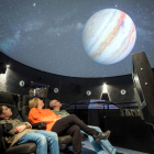 Tres visitants gaudeixen de la projecció d'una pel·lícula al planetari del Parc Astronòmic del Montsec (PAM) d'Àger.