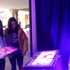 Dos alumnos de la Escuela Ondara de Tàrrega observando una de las creaciones ubicadas en un escaparate vacío de la ciudad.