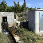 Una acequia con agua y la caseta de bombeo de la Junta de acequiaje de Lleida.