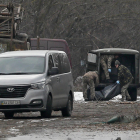 Efectivos militares trasladan el cuerpo de un hombre muerto cuando un misil ruso impactó en Kyiv.
