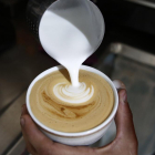 Fotografía de archivo de un hombre preparando una taza de café con leche.