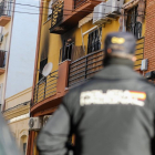 Un agende de Policía Nacional miran en dirección a la vivienda que ha sufrido el incendio en Huelva.