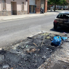 Los restos del contenedor quemado y el vehículo afectado por el fuego en la calle Antoni Solé de Lleida.