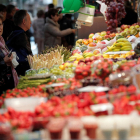 Una mujer comprando frutas y verduras en un mercado.