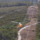 Imatge d’un helicòpter sobrevolant una línia elèctrica.