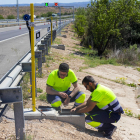 Dos operarios instalando ayer los soportes para el láser que delimitará los carriles de la autopista. 