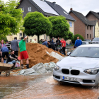 Un cotxe passa davant de diversos alemanys que netegen les destrosses de les inundacions, ahir.