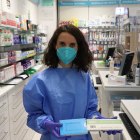 Una empleada de la Farmàcia Garrós de Lleida mostra els tests d’antígens en venda.