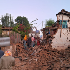 Supervivents del terratrèmol davant d’una casa esfondrada al Nepal.