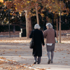 Dos dones en edat de jubilació passegen per un parc.