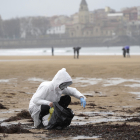 Un voluntari recollint pèl·lets en una platja de Gijón, ahir al migdia.