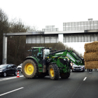 Un tractor descarrega farratge al mig de la carretera durant el bloqueig de l’autopista A15 a Argenteuil.