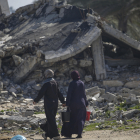 Dones palestines desplaçades passen al costat d’un edifici destruït al sud de la Franja de Gaza.