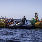 Els equips de rescat evacuen migrants a bord de l’embarcació inflable a la deriva.