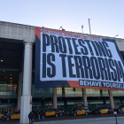 Òmnium va penjar una lona a l’aeroport del Prat amb el lema “a Espanya protestar és terrorisme”.