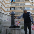 Un veí dels blocs omple una galleda d’aigua en una font.