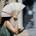 Una mujer se protege del intenso calor con un abanico, en una fotografía de archivo.