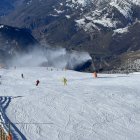 Esquiadors baixant per una pista on funcionen canons de producció de neu a Baqueira