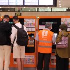 Diverses persones a les màquines d'autovenda de Rodalies de l'estació de Sants de Barcelona el primer dia en vigor dels abonaments gratuïts