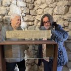 Dos miembros de la Associació d'Amics de la Vall de Caboet, Mercè Casanova y Montserrat Riu, mirando una reproducción de los Greuges de Guitard Isarn, señor de Caboet.