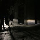 Un carrer del Barri Gòtic de Barcelona totalment fosc, amb la il·luminació d'un vehicle com a única llum.