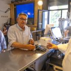 L’alcalde, Toni Bosch (dreta), mostra el funcionament de la retirada d’efectiu al bar social. - JORDI ECHEVARRIA