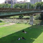 Diverses persones a l’ombra a la canalització del Segre a Lleida.