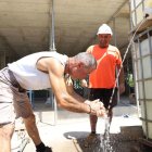 Treballadors refrescant-se amb aigua al costat d’una obra de construcció en plena canícula. - MAGDALENA ALTISENT