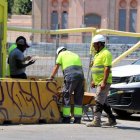 Treballadors es protegeixen del sol en plena onada de calor.; Array