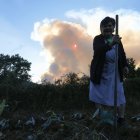 Una dona davant la columna de fum d’un incendi a Lugo. - EFE