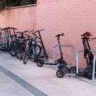 Diversos patinets elèctrics i bicicletes aparcades en tanques