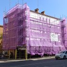 Operaris cobreixen la façana de maons amb planxes blanques. - S.E.