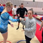 Àngela Mora, amb dessuadora grisa, saluda una altra gimnasta.