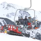 Un grup d’esquiadors en un remuntador de Baqueira-Beret amb màquines trepitjaneu al fons. - EDGAR ALDANA