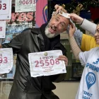 Raúl, el ‘calb de la sort’, subjectant els dos números premiats que van agraciar Sant Boi. - ACN / ALBERT SEGURA